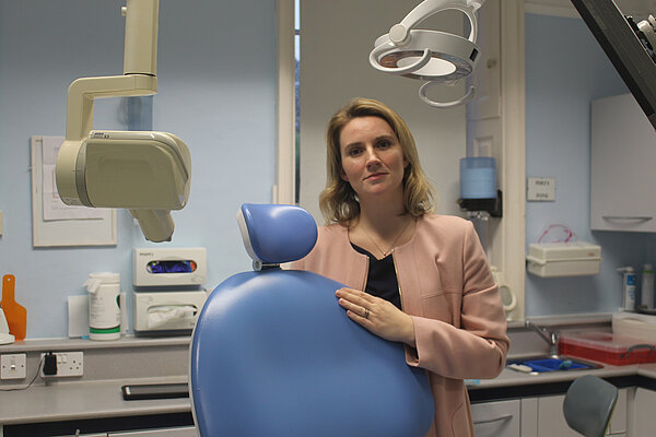Jess Brown-Fuller standing next to a dentist's chair
